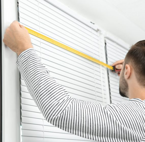 Young man installing window shades at home Young man installing window shades at home
