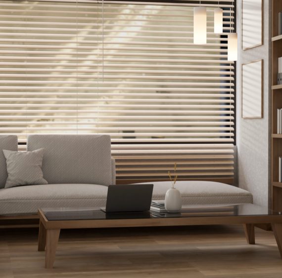 A cozy, contemporary minimalist living room features a large sofa and a laptop on a coffee table. A cozy, contemporary minimalist living room features a large sofa, a laptop on a minimalist coffee table, a bookshelf, a window with sunshades, and parquet flooring. 3d render, 3d illustration